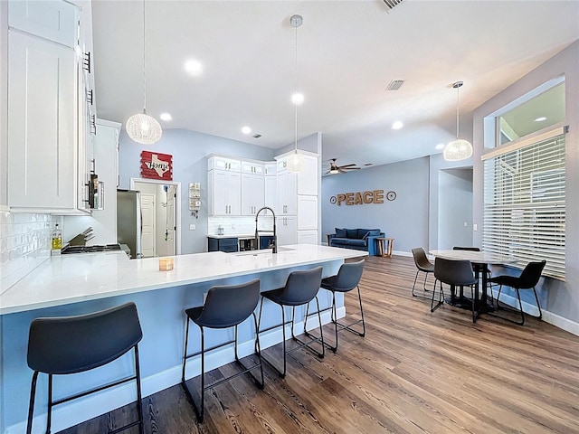 kitchen with a ceiling fan, a sink, backsplash, white cabinetry, and dark wood-style flooring