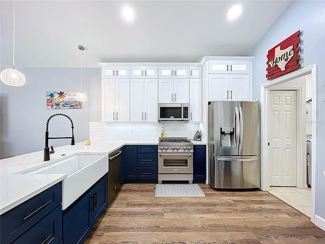 kitchen with blue cabinetry, a sink, stainless steel appliances, light wood-style floors, and white cabinetry