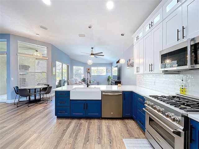 kitchen featuring a peninsula, stainless steel appliances, blue cabinets, a ceiling fan, and a sink