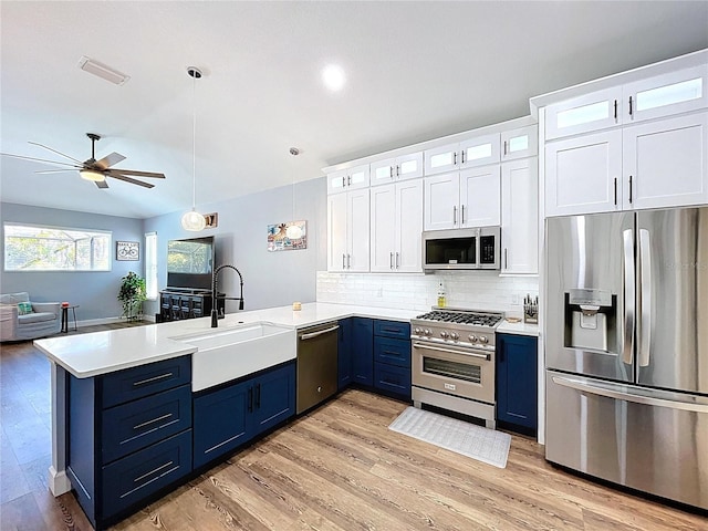 kitchen featuring a peninsula, a sink, ceiling fan, stainless steel appliances, and blue cabinets