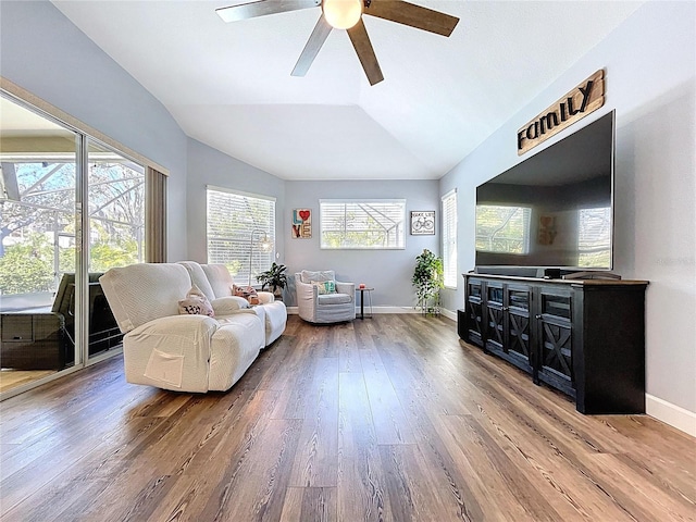 living area with baseboards, wood finished floors, a ceiling fan, and vaulted ceiling