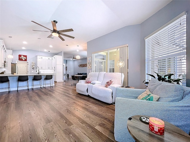 living room with vaulted ceiling, a ceiling fan, and wood finished floors