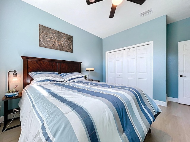 bedroom featuring visible vents, light wood-style flooring, a closet, baseboards, and ceiling fan