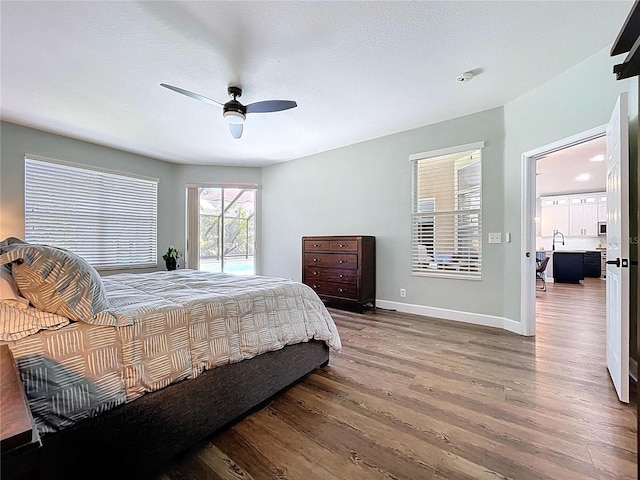 bedroom featuring a sink, ceiling fan, baseboards, and wood finished floors