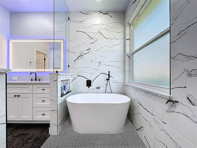 full bath featuring vanity, tile walls, and a freestanding bath