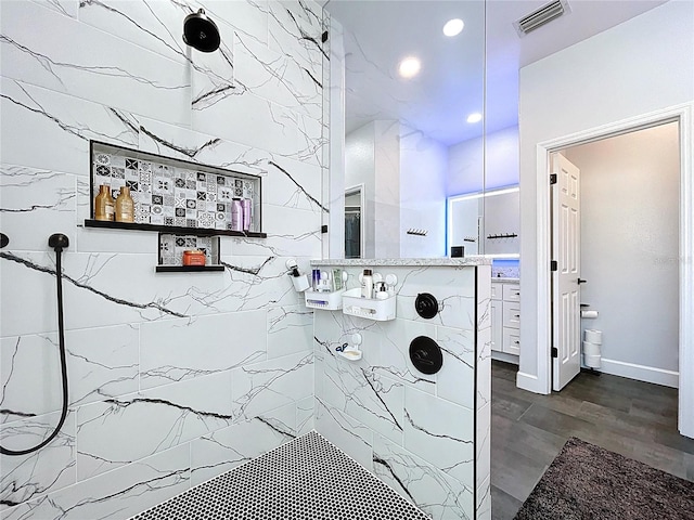 bathroom with visible vents, wood finished floors, recessed lighting, baseboards, and tiled shower