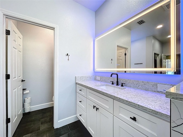 bathroom featuring vanity, toilet, baseboards, and visible vents