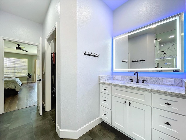 ensuite bathroom featuring vanity, wood finished floors, a ceiling fan, baseboards, and ensuite bath