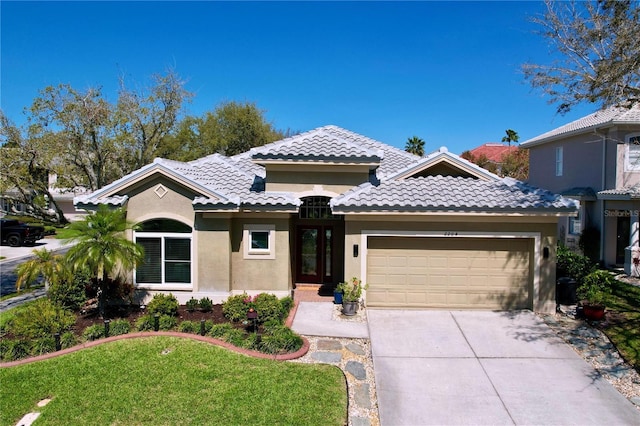 mediterranean / spanish-style home with a tile roof, stucco siding, concrete driveway, and a garage