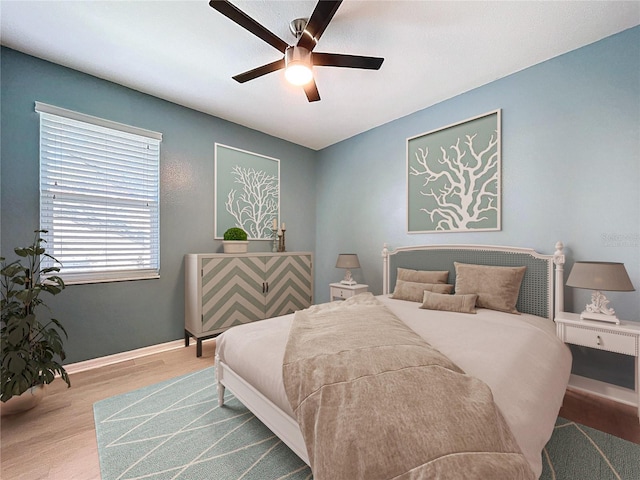 bedroom with a ceiling fan, wood finished floors, and baseboards