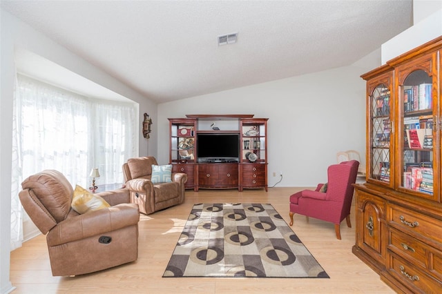 living area featuring visible vents, a textured ceiling, light wood-style floors, and lofted ceiling