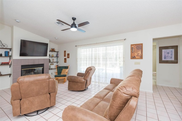 living area featuring visible vents, ceiling fan, lofted ceiling, a fireplace, and light tile patterned flooring