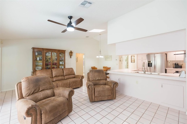 living room with vaulted ceiling with skylight, light tile patterned flooring, visible vents, and ceiling fan