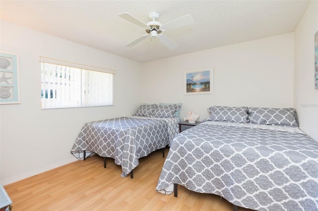 bedroom with baseboards, a textured ceiling, wood finished floors, and a ceiling fan