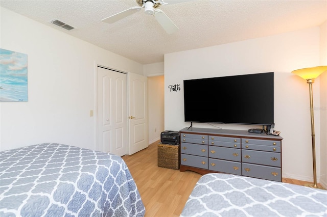 bedroom with visible vents, ceiling fan, light wood-style floors, a closet, and a textured ceiling