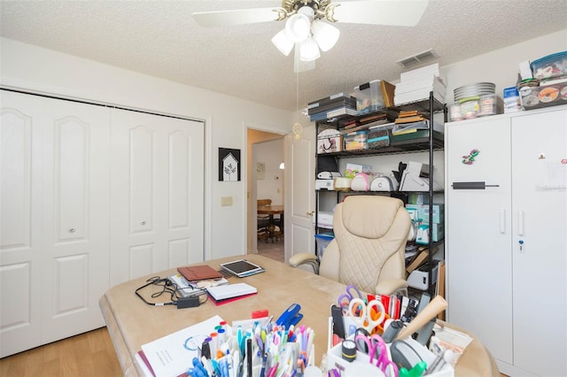 home office with ceiling fan, wood finished floors, visible vents, and a textured ceiling