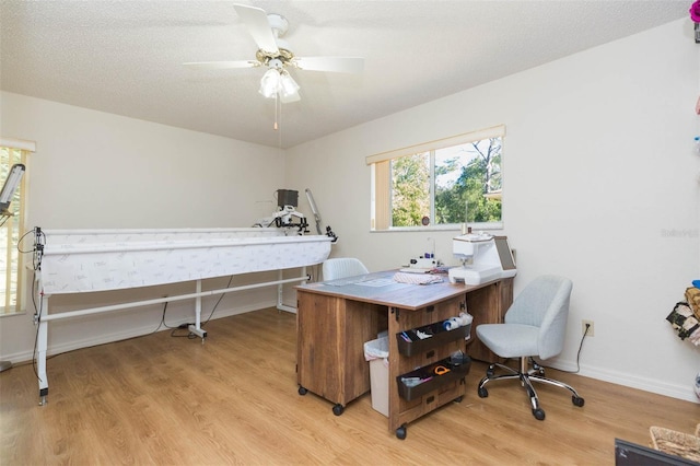 bedroom featuring a ceiling fan, baseboards, light wood-type flooring, and a textured ceiling