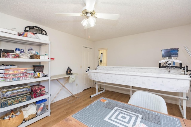 bedroom featuring ceiling fan, wood finished floors, baseboards, and a textured ceiling