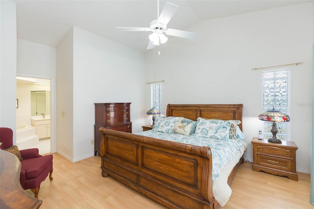 bedroom featuring a ceiling fan, baseboards, ensuite bath, vaulted ceiling, and light wood-style floors