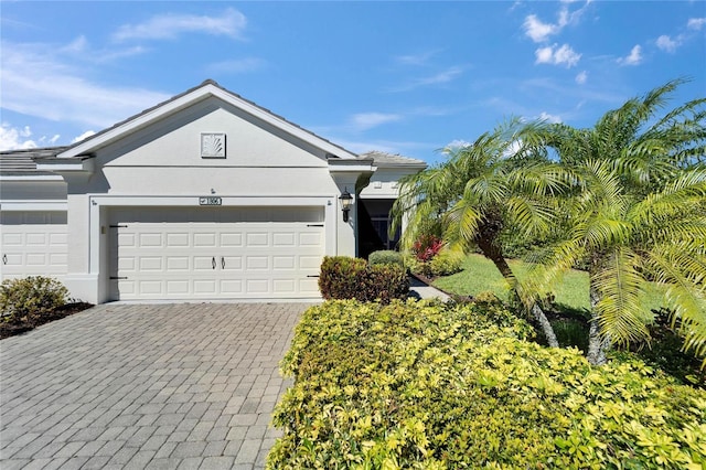 single story home with decorative driveway, a garage, and stucco siding