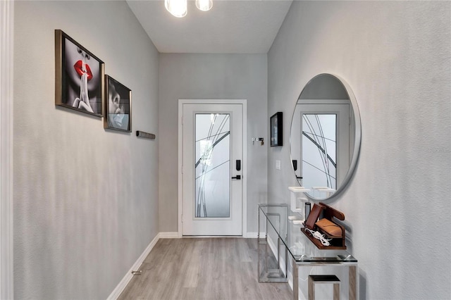 doorway to outside featuring baseboards and wood finished floors