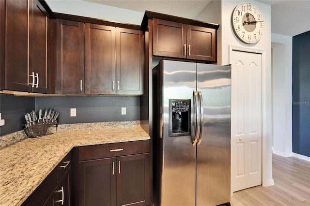 kitchen with light stone countertops, baseboards, stainless steel fridge with ice dispenser, dark brown cabinetry, and light wood-type flooring