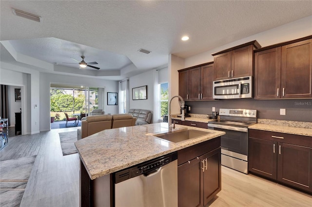 kitchen with stainless steel appliances, a raised ceiling, visible vents, and open floor plan