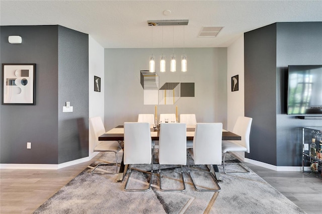 dining area featuring visible vents, baseboards, and wood finished floors