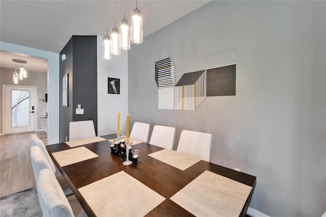 dining room featuring a chandelier, a textured ceiling, and wood finished floors