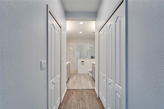 hall featuring recessed lighting, wood finished floors, and a textured wall