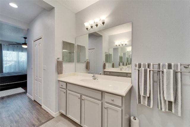 ensuite bathroom with ceiling fan, baseboards, ensuite bathroom, wood finished floors, and vanity