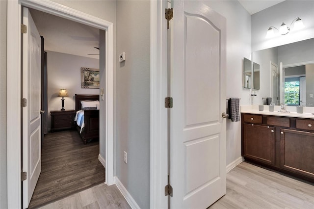 bathroom with connected bathroom, baseboards, wood finished floors, and vanity