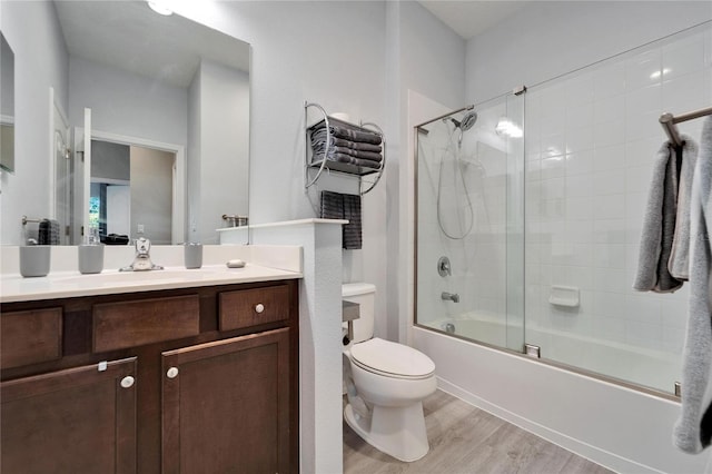 bathroom featuring vanity, toilet, wood finished floors, and shower / bath combination with glass door