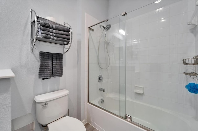 full bathroom featuring combined bath / shower with glass door and toilet