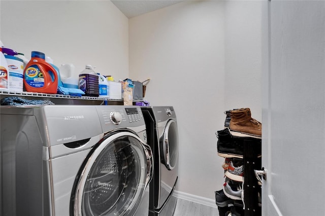 clothes washing area with laundry area, wood finished floors, separate washer and dryer, and baseboards