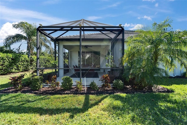 exterior space with glass enclosure, a lawn, and ceiling fan