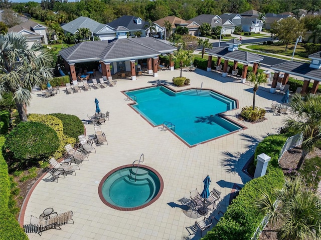 pool featuring a residential view, fence, a hot tub, and a patio area