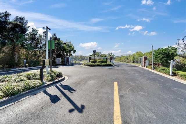 view of street with a gate, curbs, and a gated entry