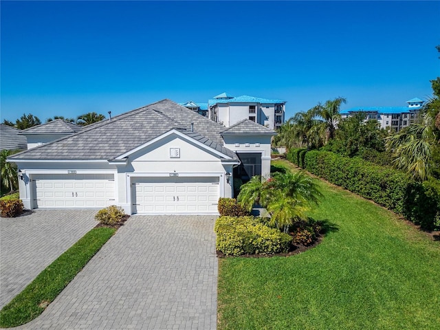 view of front of property featuring an attached garage, decorative driveway, and a front yard