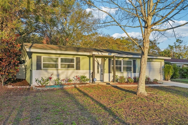 ranch-style house featuring stucco siding, driveway, a front yard, and a garage