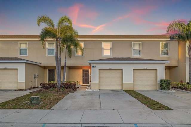 view of property with stucco siding, driveway, and a garage