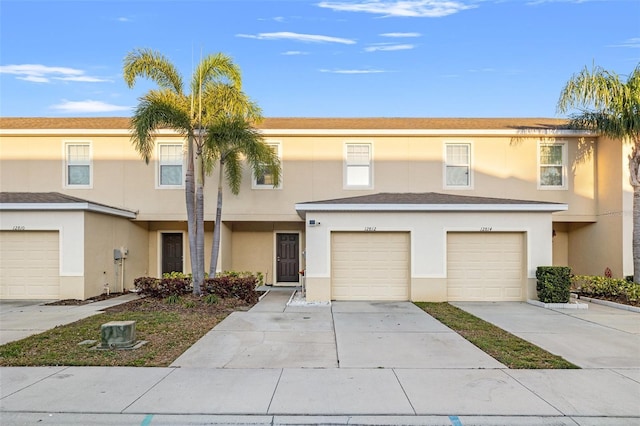 multi unit property featuring a garage, driveway, and stucco siding