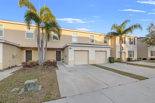 townhome / multi-family property with a garage, driveway, and stucco siding