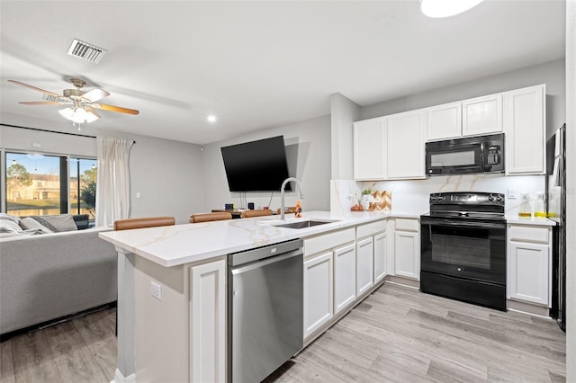 kitchen featuring open floor plan, a peninsula, black appliances, and a sink