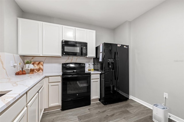 kitchen with light stone counters, light wood-style flooring, white cabinets, and black appliances