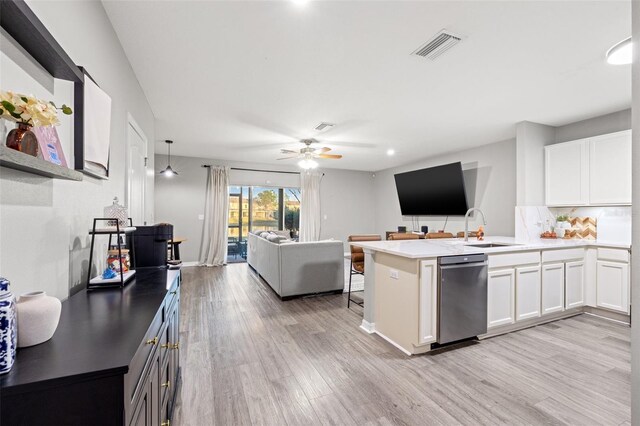 kitchen with open floor plan, a peninsula, white cabinetry, and a sink