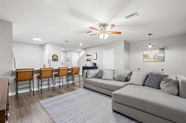 living area with indoor wet bar, wood finished floors, visible vents, and a ceiling fan