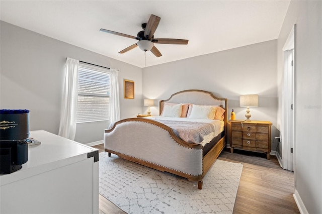 bedroom featuring baseboards, light wood-style floors, and ceiling fan