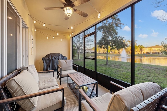 sunroom featuring a ceiling fan and a water view