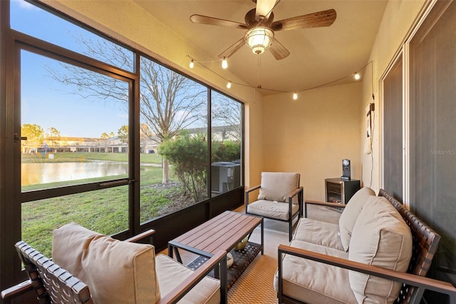 sunroom featuring track lighting, ceiling fan, and a water view